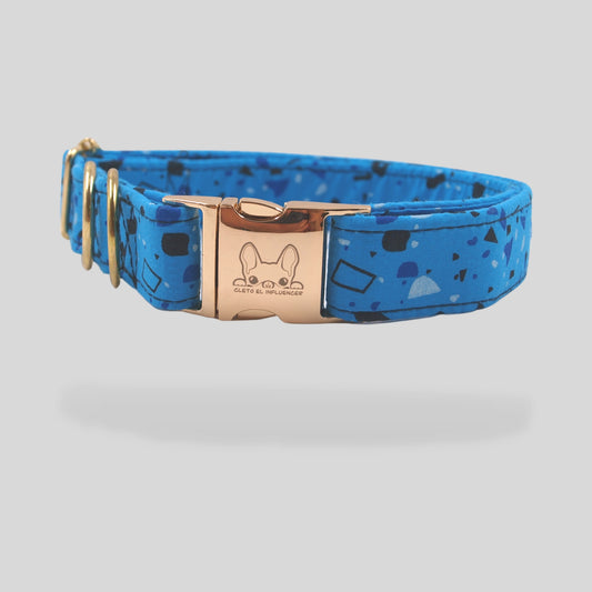 Collar para mascota con herrajes dorados, el collar es azul con formas geométricas en tonos azules.